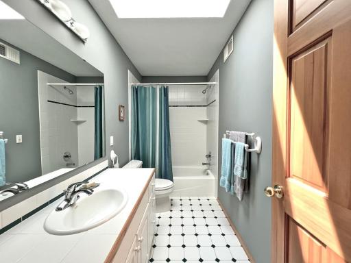 Full bathroom upstairs with plentiful natural light through skylight