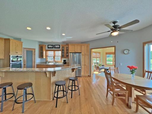 Open kitchen and dining area featuring hardwood floors, center island, plentiful cabinetry & counterspace, pantry, and abundant natural light