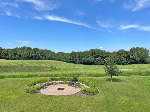 Panoramic backyard view overlooking the 17th fairway, rolling hills, and a circular patio with fire pit