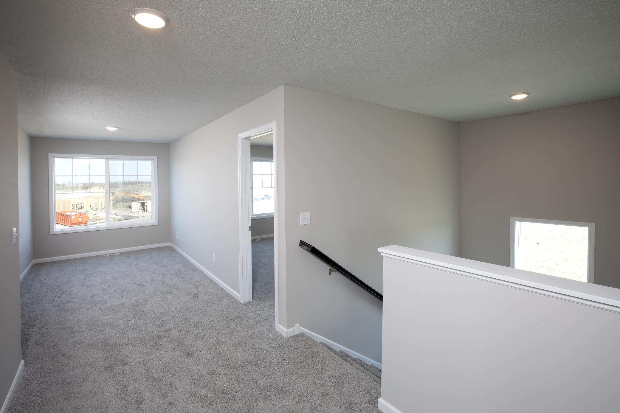 PHOTO OF A DIFFERENT HOME WITH SIMILAR PLAN. FINISHES MAY VARY. Upper Level Hallway View to Staircase and Versatile Loft area.