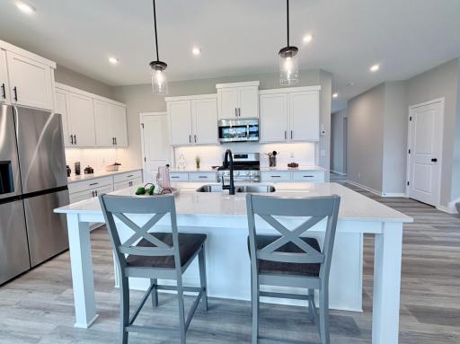 9686 32nd St NE- Kitchen highlights also include under cabinet lights, ceramic tile backsplash, quartz countertops, soft close doors/drawers, and base cabinet trash/recycling pullout.