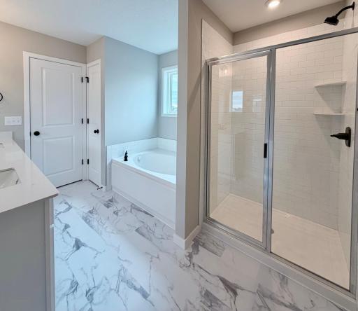 Primary Suite Deluxe Bath features a Soaking Tub, Separate Shower with Ceramic Tile Wall Surround, and Linen Closet.