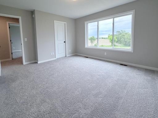 9686 32nd St NE- Primary Suite features Two Walk-in Closets, Private Deluxe Bath, and backyard views.