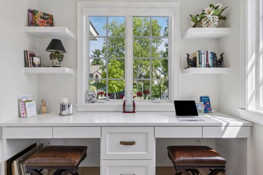 French pocket doors open to a secluded cozy office area features two desks, and three windows.