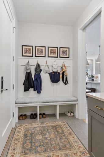 A wonderful mudroom with a large closet, a built-in cabinet and designed for an elevator shaft, and a charming built-in bench with hooks and accessed the garage.