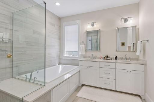 The luxurious primary bathroom features a deep, soaking tub and a large, walk-in shower and a double vanity