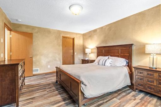 Main floor primary bedroom with updated flooring and walk-in closet with custom organizers by Closets By Design.