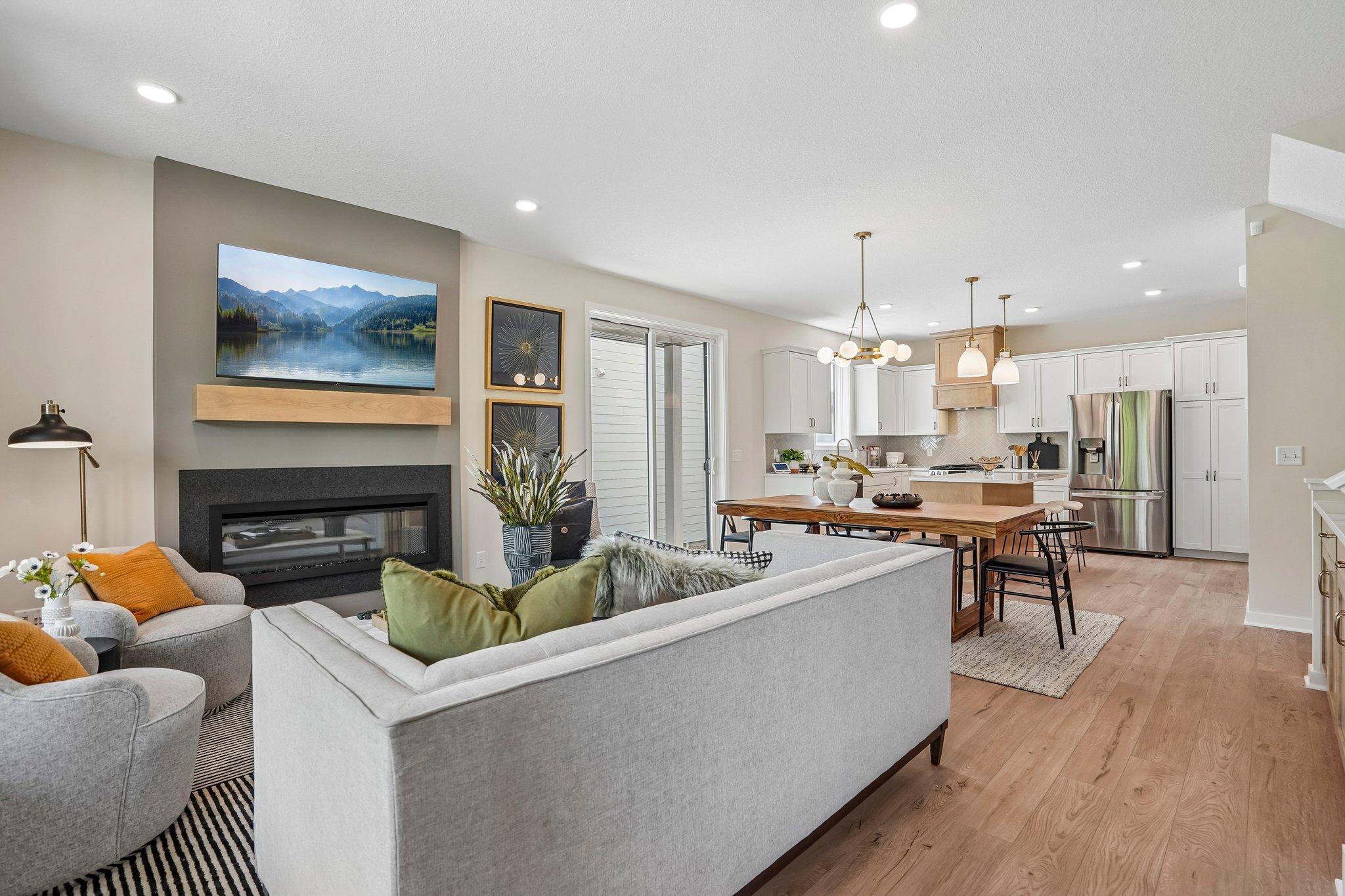 Sophisticated main level with durable SPC flooring, anchored by a statement fireplace with granite surround and wood mantle.