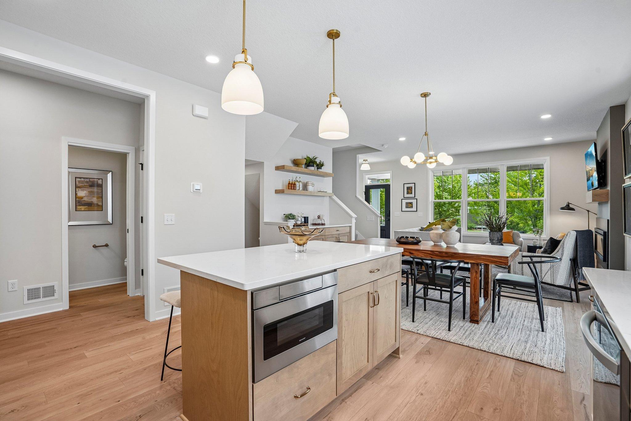 Gourmet kitchen design showcases painted white cabinetry, stained wood hood and island, herringbone backsplash and marble-look quartz countertops.