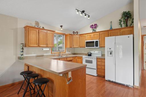 Great kitchen featuring ample cabinet and countertop space, a breakfast bar, new refrigerator, and microwave. Designed for both functionality & entertaining, this kitchen offers plenty of room for meal prep and gathering with family and friends.