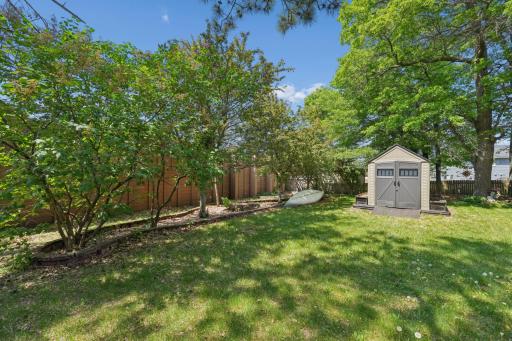 Beautiful flowering trees and numerous garden beds line the backyard, creating a picturesque outdoor setting filled with color and natural beauty.