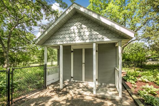 Accessory/Garden shed with a covered entrance and paver stone sidewalk.
