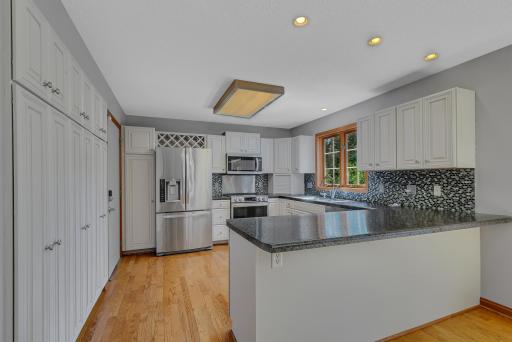 The kitchen has been tastefully refreshed with freshly painted cabinetry, a tiled backsplash, and modern LED recessed lighting.