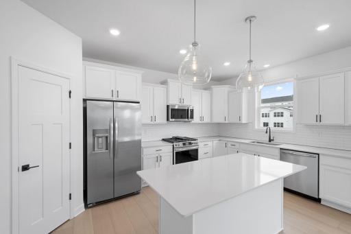 This stylish and multifunctional kitchen comes complete with brand-new stainless steel appliances, sleek quartz countertops and Shaker-style cabinetry.
