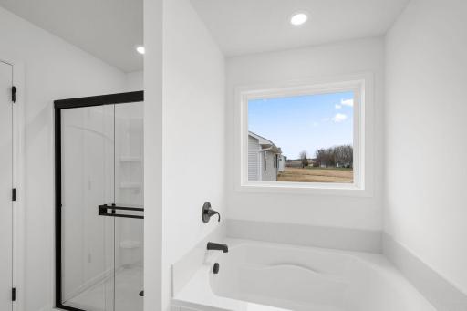 A glass-enclosed shower and separate soaking tub contribute to the bathroomâs spa-like atmosphere