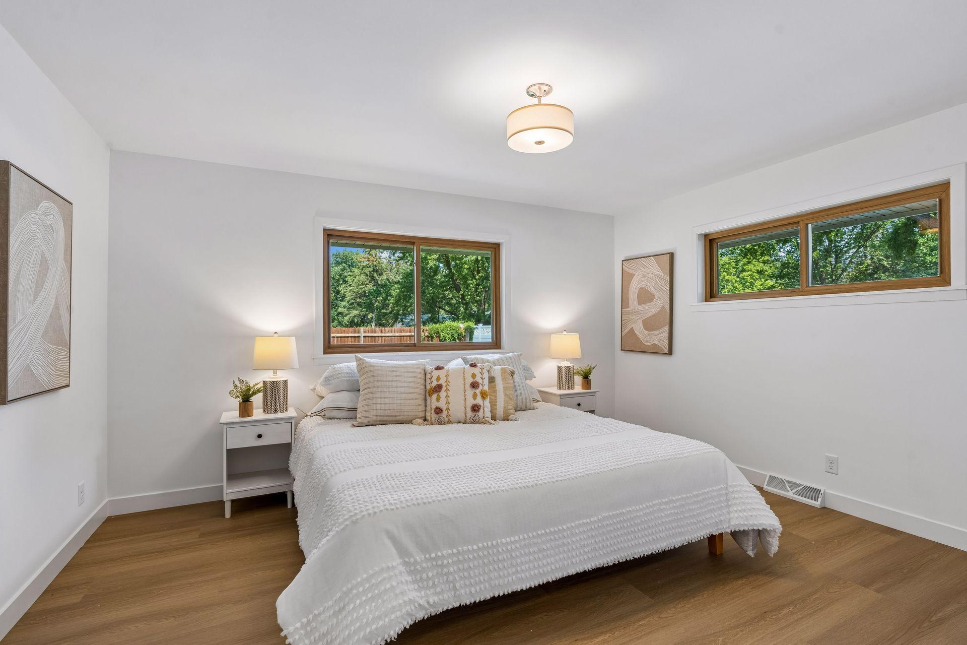 14x12 Main floor Bedroom #1 with East and north-facing updated windows, new paint, New trim and closet doors, new luxury vinyl flooring, and lighting.