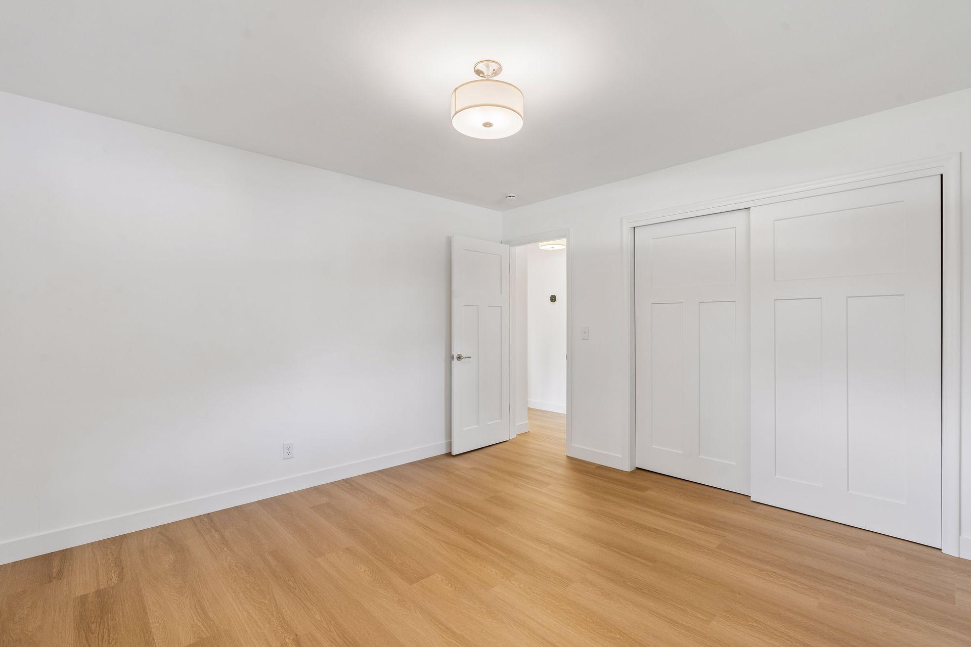 13x12 Main floor Bedroom #2 with East and South-facing updated windows, new paint, New trim and closet doors, new luxury vinyl flooring, and lighting.
