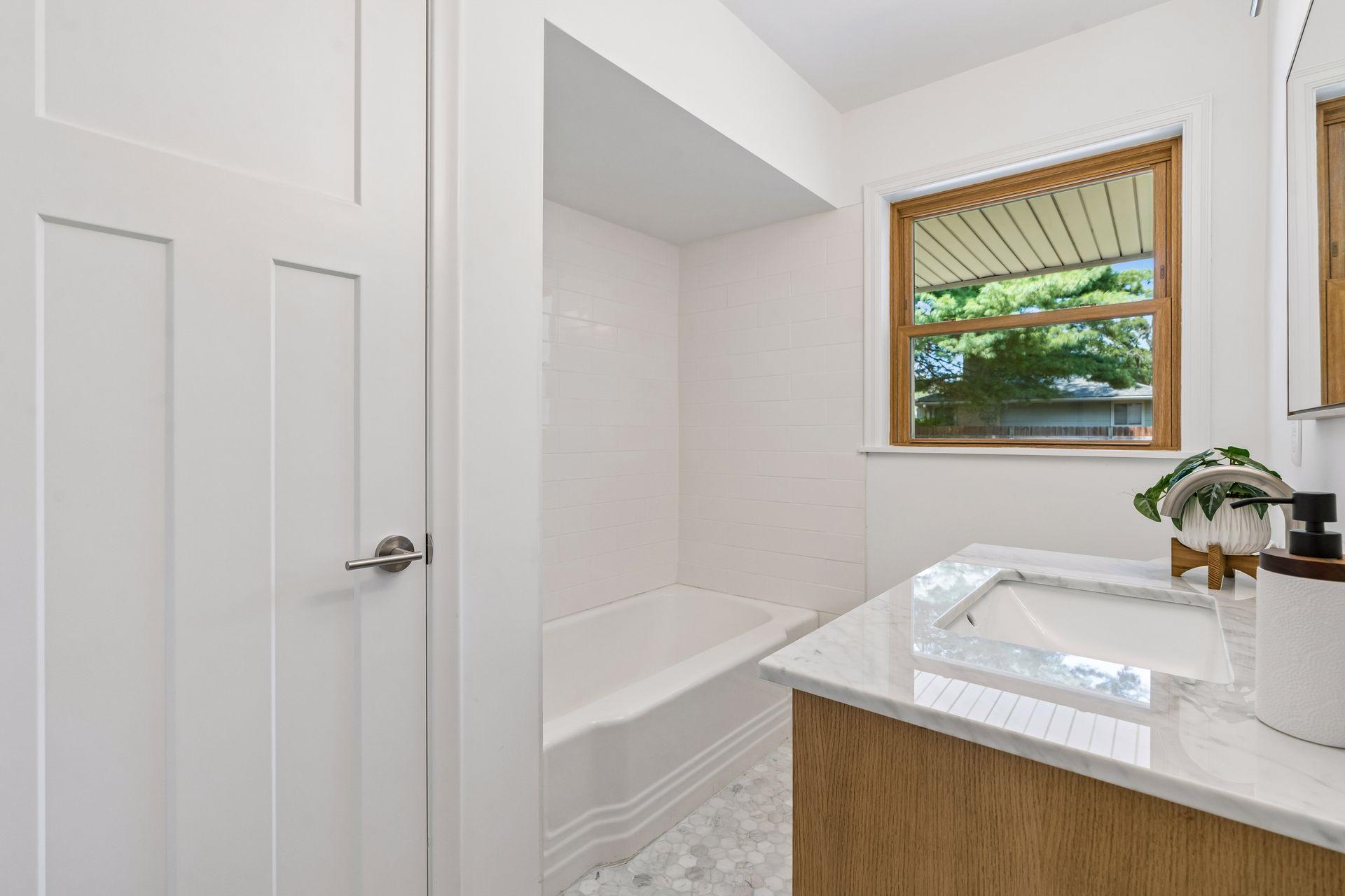 Main Floor: Full bathroom with updated Subway tile, White oak Room and Board vanity with marble top and Mirror, New toilet, New lighting, and Marble flooring