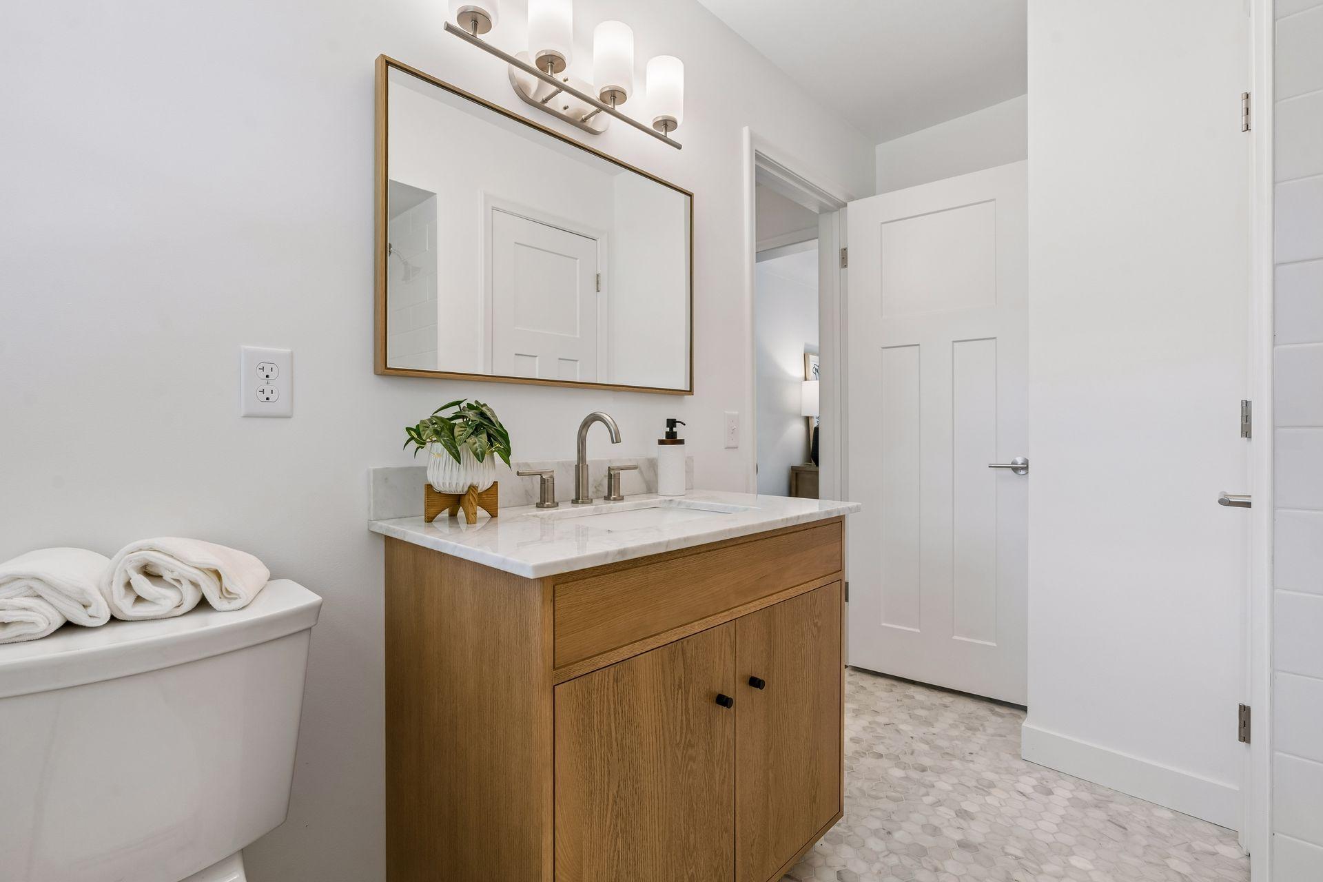 Main Floor: Full bathroom with updated Subway tile, White oak Room and Board vanity with marble top and Mirror, New toilet, New lighting, and Marble flooring