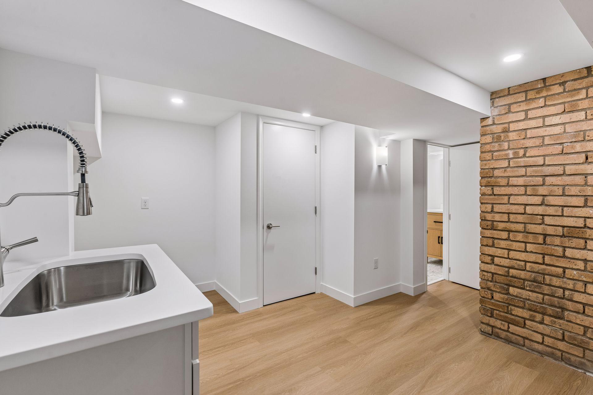 34x14 lower-level family room with East-facing updated glass block windows, new paint, new luxury vinyl flooring, and lighting. New Sink for a possible second kitchen or Bar.