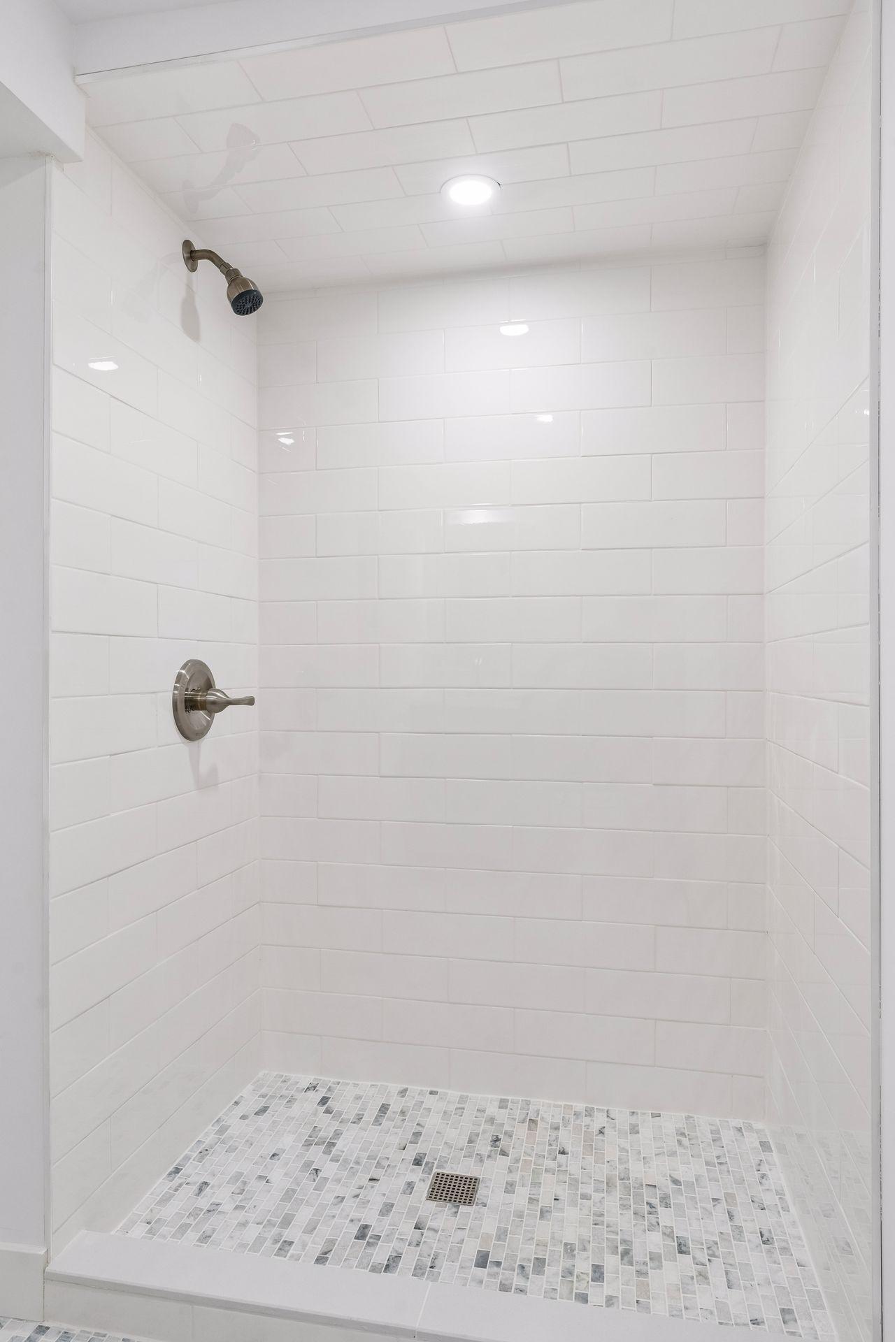 Lower Level 3/4 bathroom with updated Subway tile shower, White oak vanity with quartz top and Room and Board Mirror, New toilet, New lighting, and Marble flooring