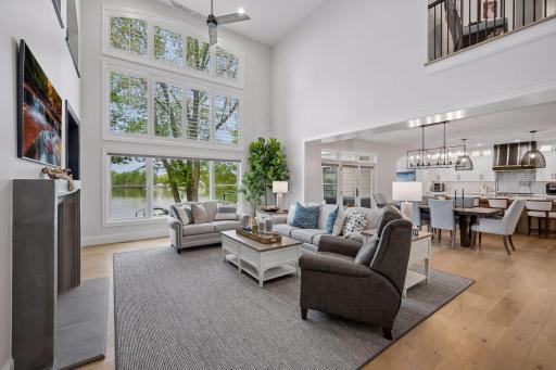 Living room with soaring 19 foot ceilings, a wall of windows for natural light, custom built ins and a gas fireplace.
