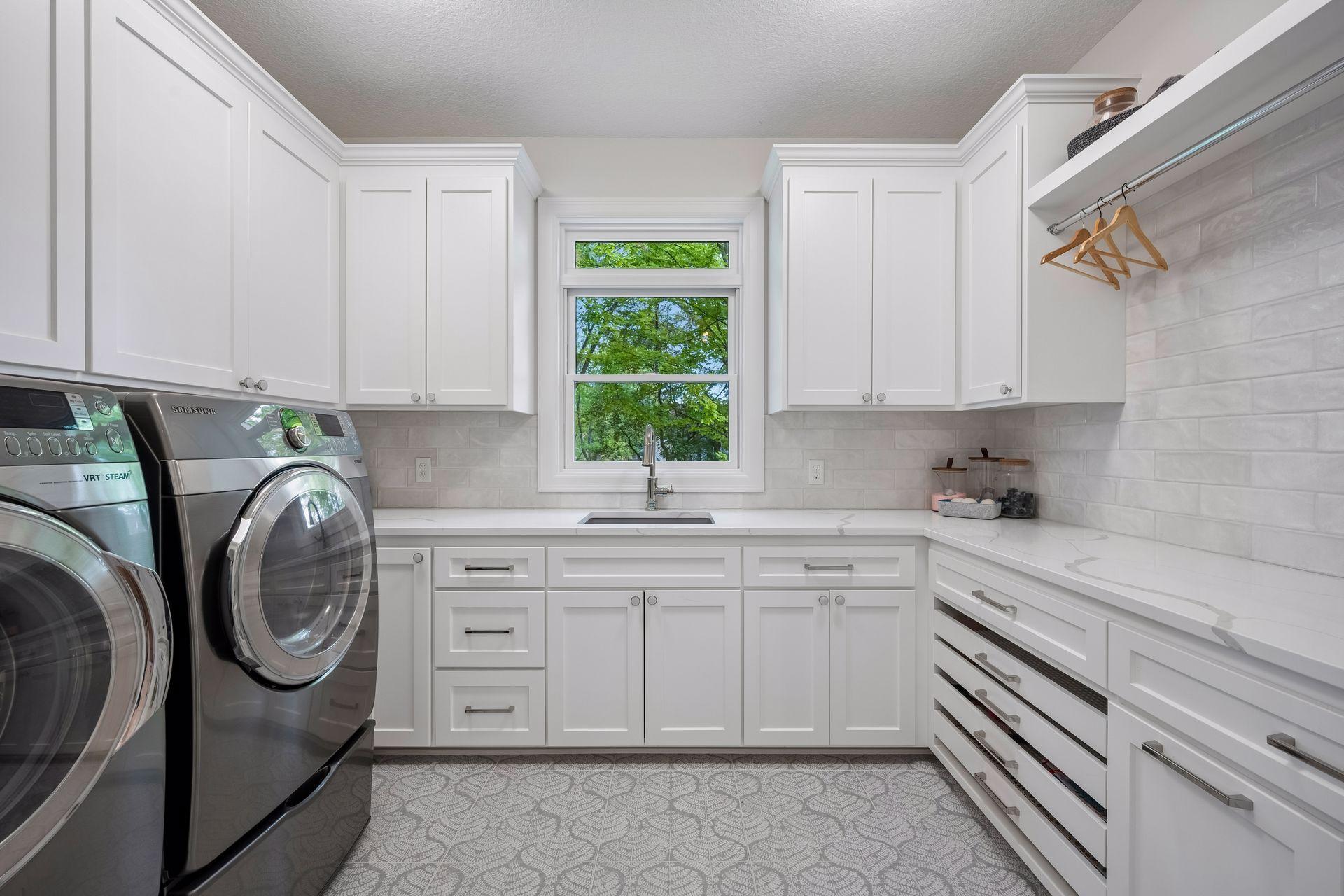 Main floor laundry with quartzite counter tops and an abundance of cabinetry/storage.