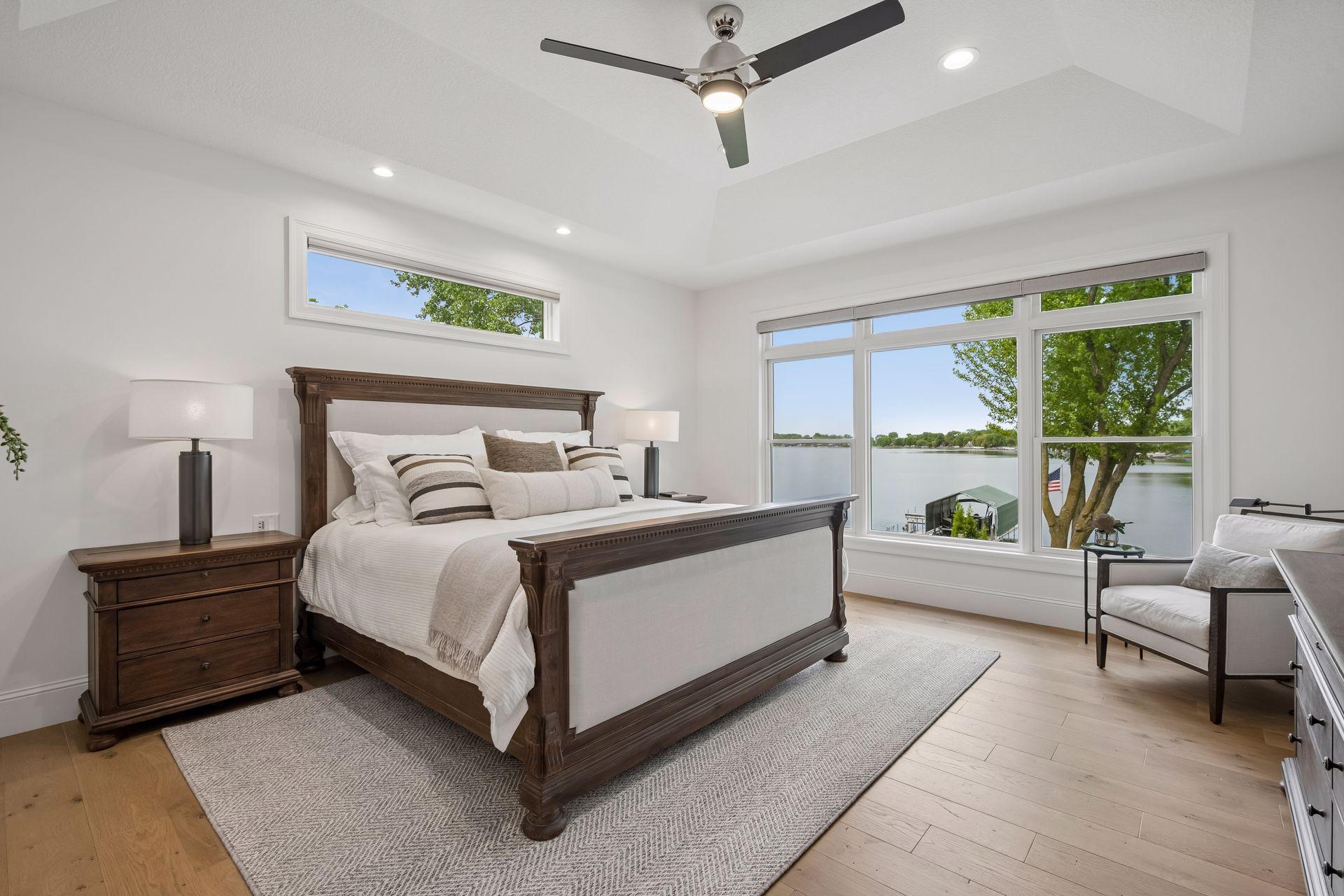 Main floor primary bedroom with tray vault ceiling, hardwood floors, and private en suite