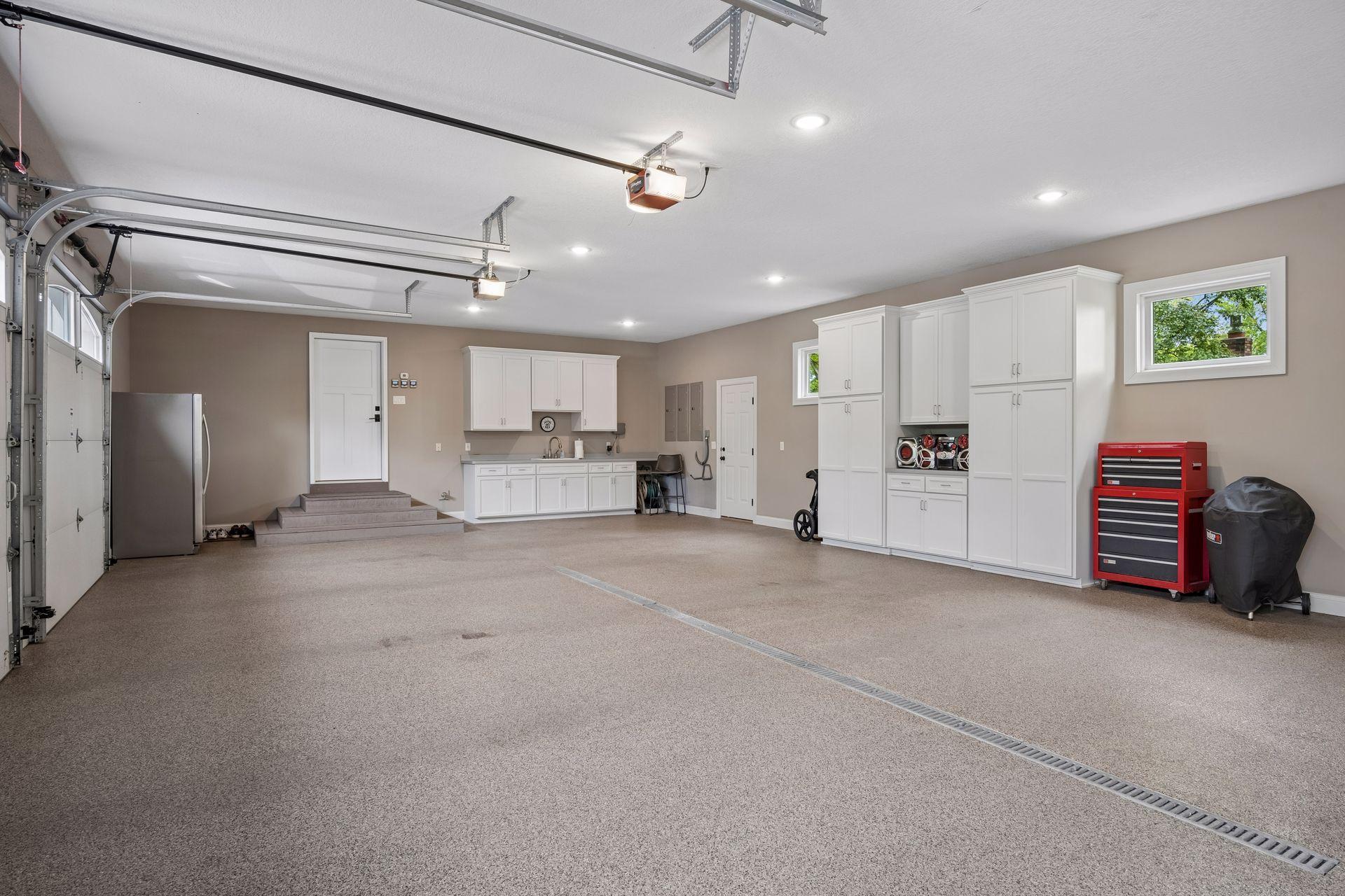Large attached 3 stall garage with floor drains, in floor heat, storage and sink.