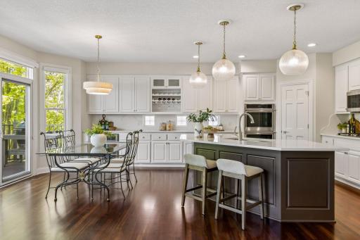 The open, bright, and inviting layout showcases a gourmet eat-in kitchen with a large center island, quartz countertops, custom cabinetry, high-end appliances, and a walk-in pantry.