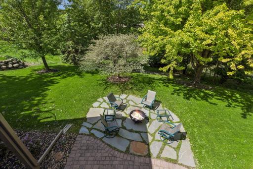 A large brick paver patio and custom flagstone firepit area create an inviting outdoor oasis perfect for relaxing and entertaining.