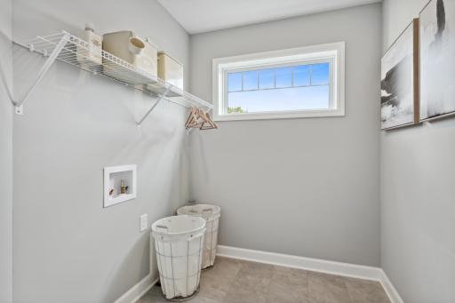 (Photo of a decorated model, actual finishes will vary.) The laundry room features washer and dryer hook-ups and shelving for storage.