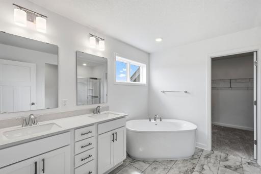 Dual sinks, a glass-enclosed shower and a separate soaking tub contribute to the spa-like atmosphere of the en-suite bathroom