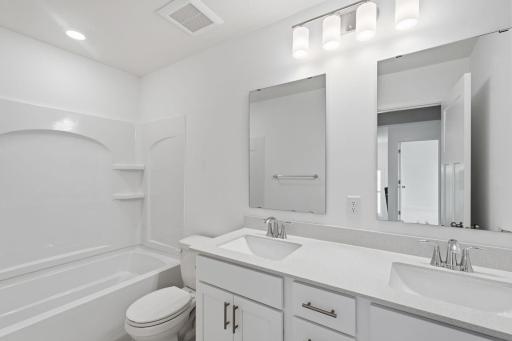 This shared full bathroom features dual sinks and a shower-tub combination.