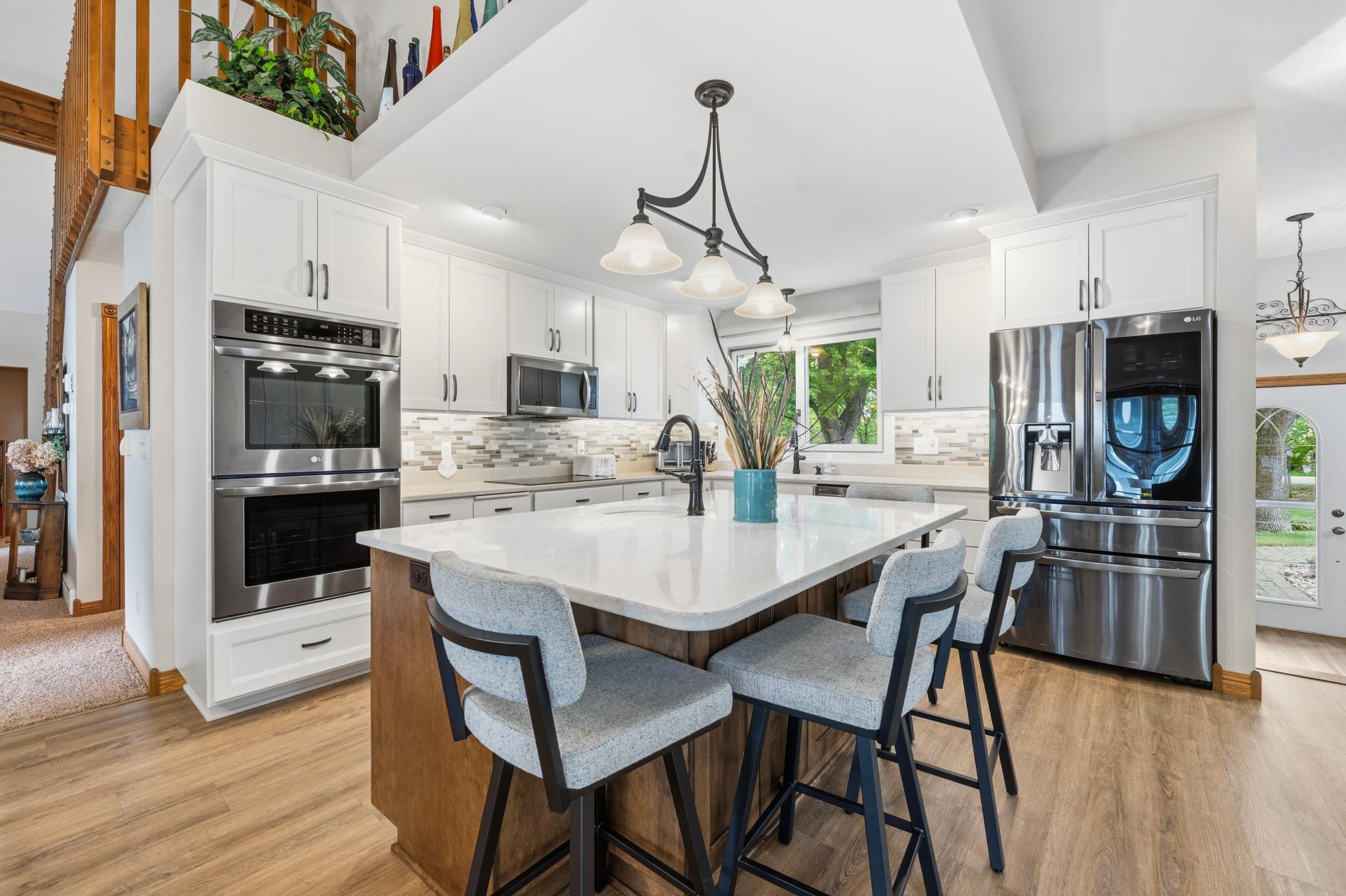 The modern kitchen features crisp white cabinetry, sleek Quartz countertops, and a stylish backsplash.