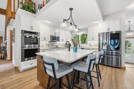 The modern kitchen features crisp white cabinetry, sleek Quartz countertops, and a stylish backsplash.