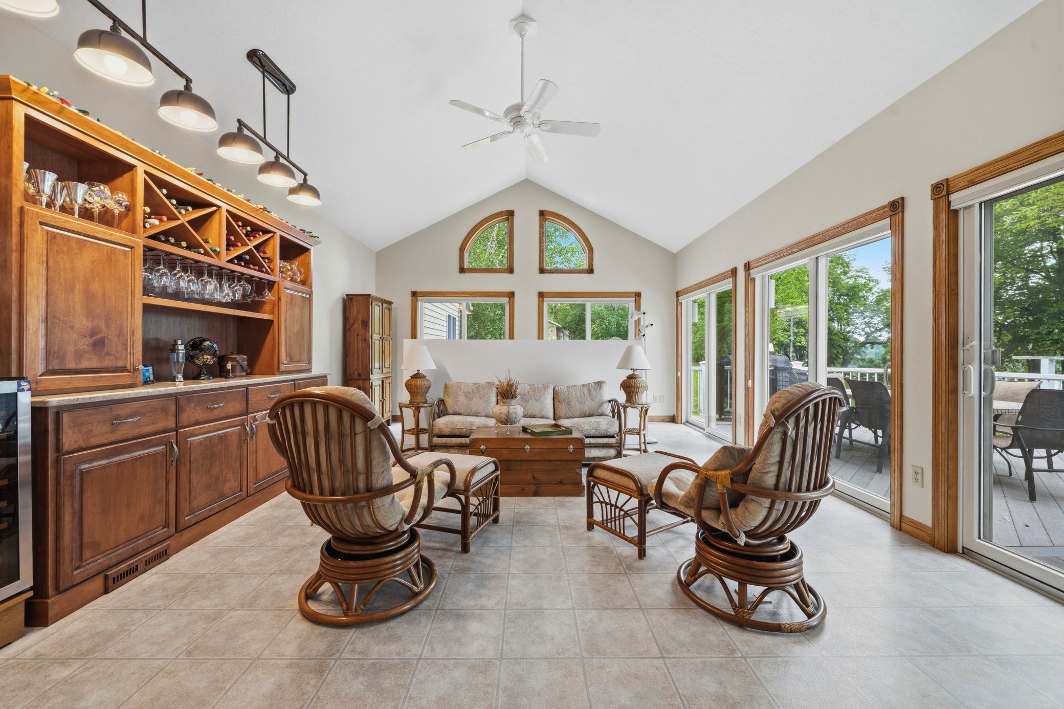 Transition into the sunroom with vaulted ceilings, a built-in bar, and a ceiling fan for added comfort.