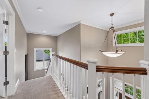 Overlooking the dramatic two-story foyer below, the approach to the primary suite creates a sense of arrival, setting the stage for the private retreat beyond.