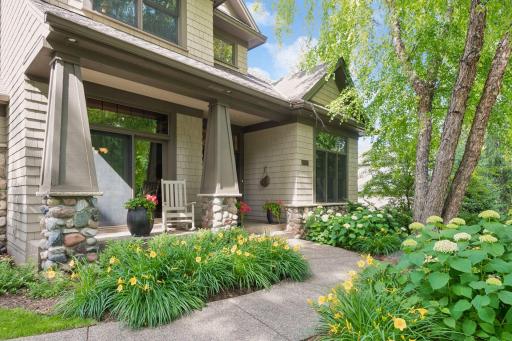 A lovely garden path leads to the welcoming covered front porch, where colorful blooms and thoughtful landscaping create a warm arrival for both family and guests.