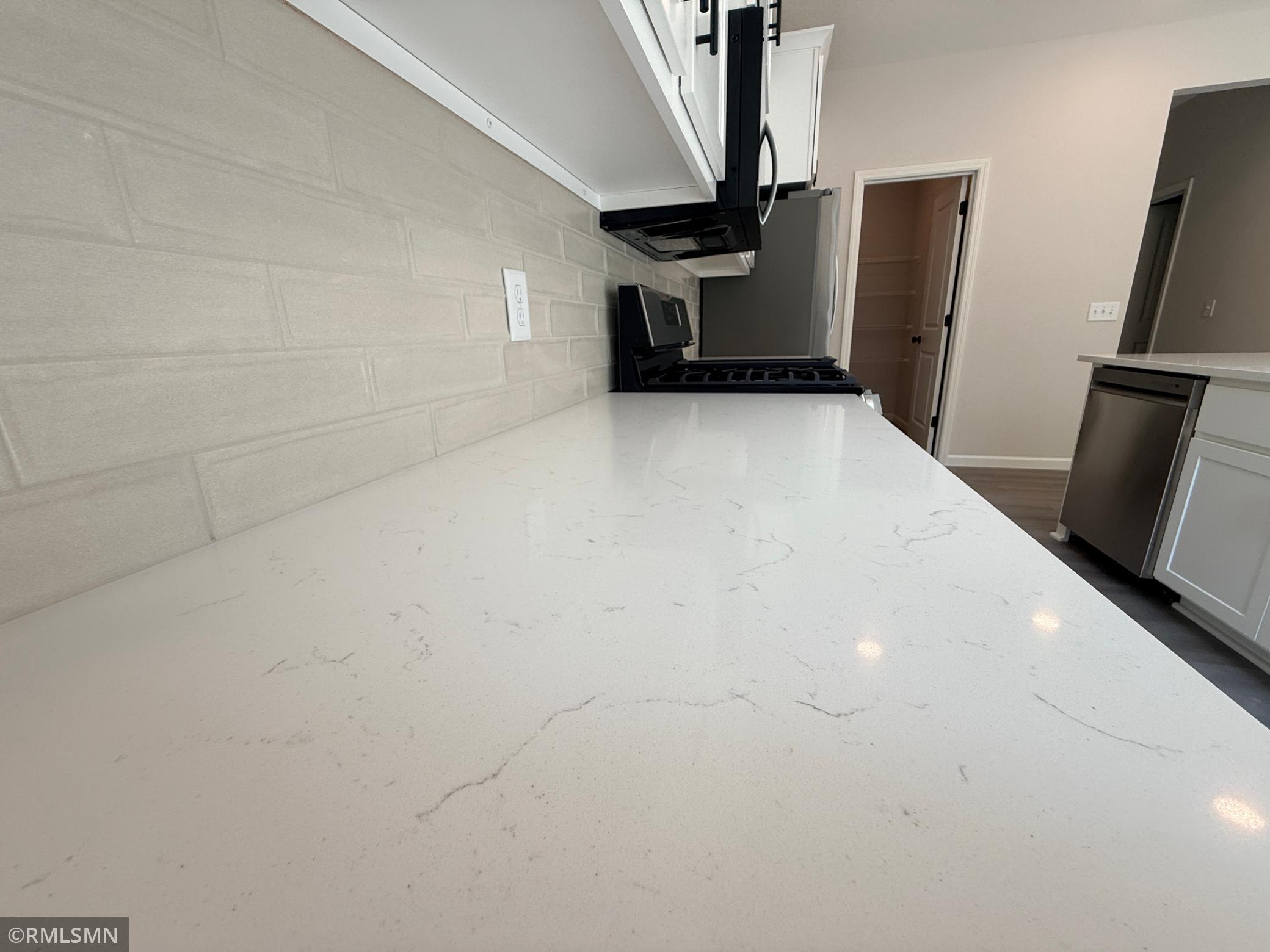 Close up of the quartz countertop and ceramic tile backsplash.