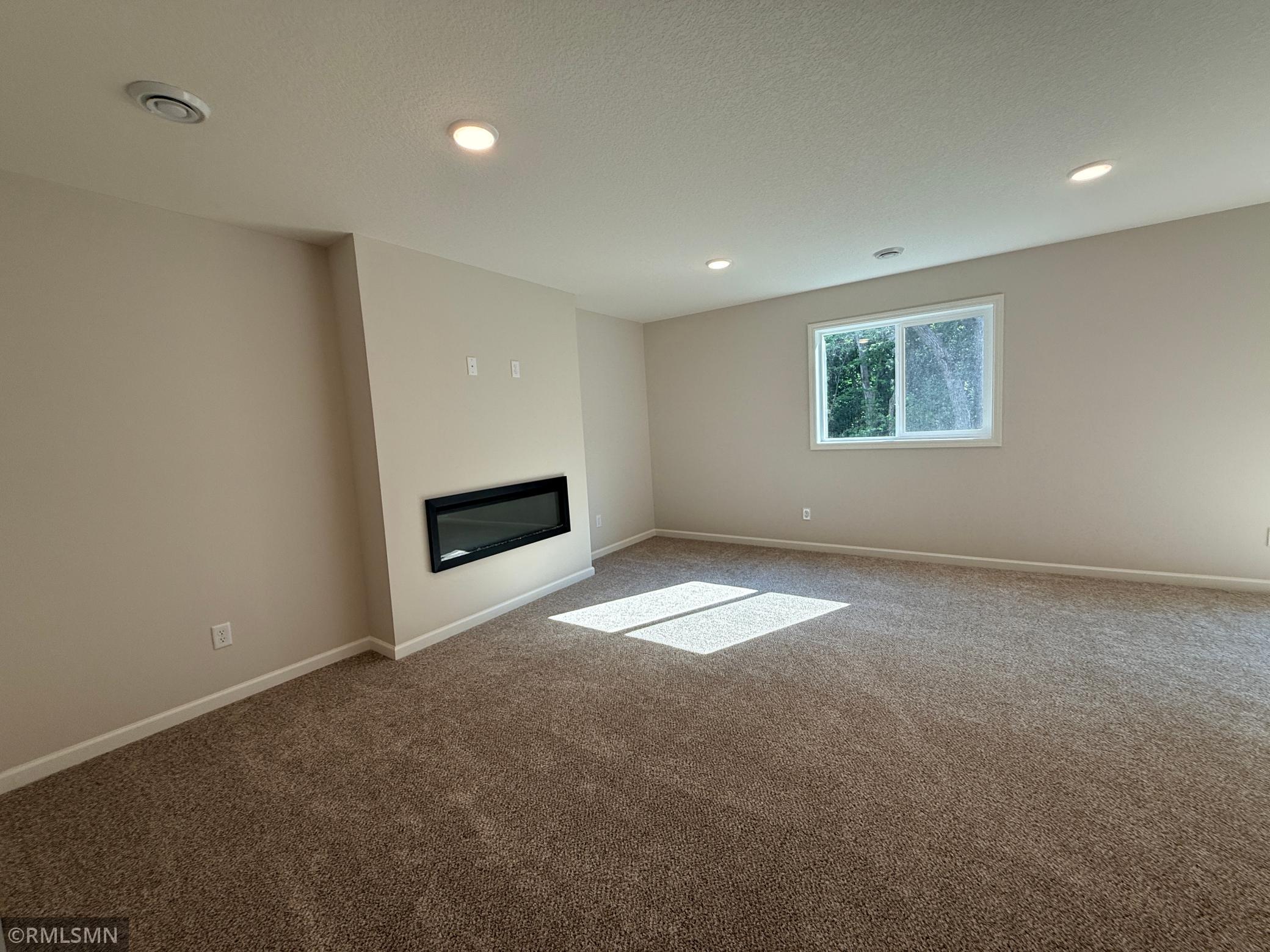 The lower level family room includes a 2nd fireplace - this one is a sleek electric fireplace!