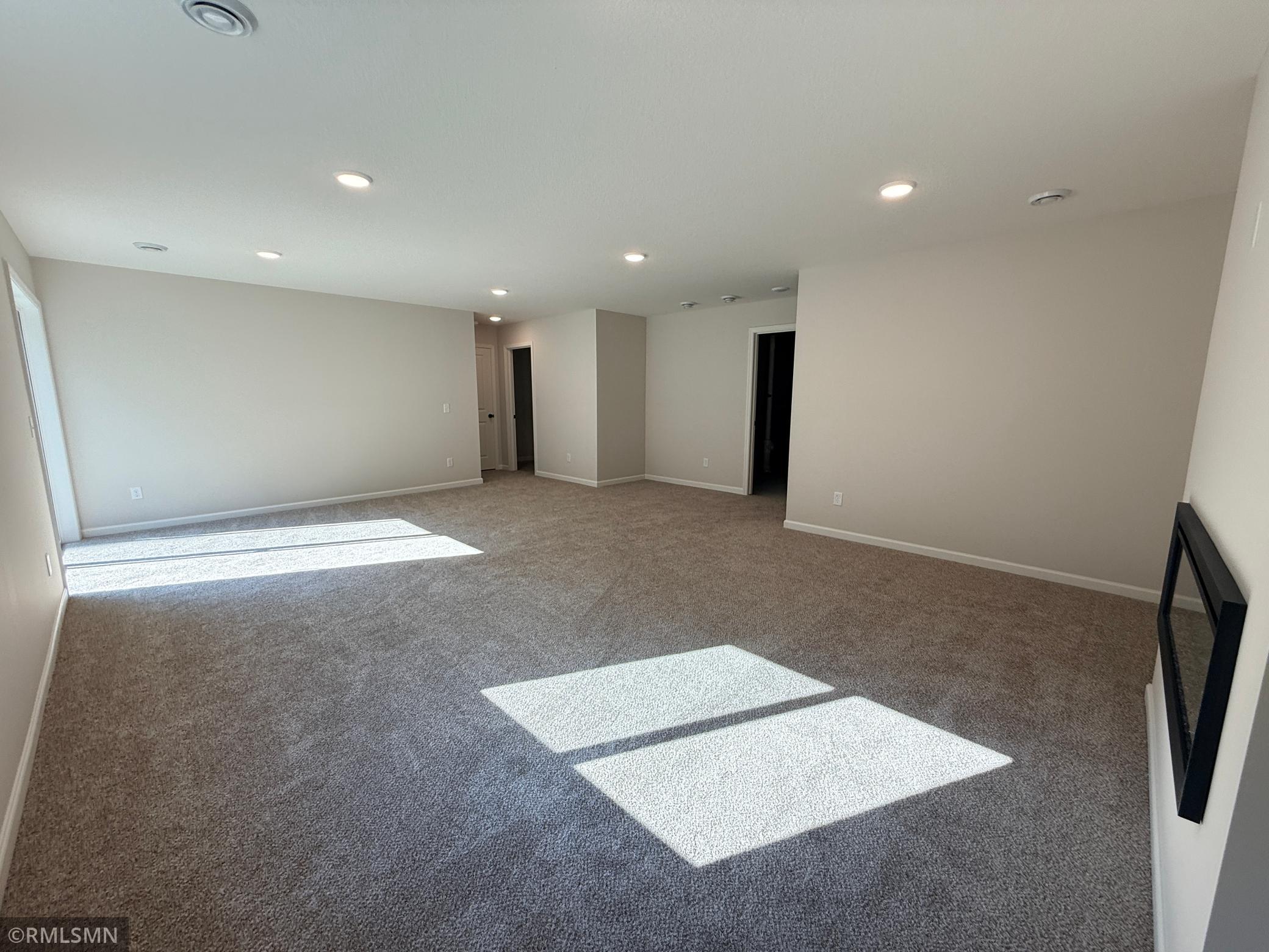 Opposite view of lower level family room - utility room in middle back of photo, bedroom and bath doors on middle left of photo.