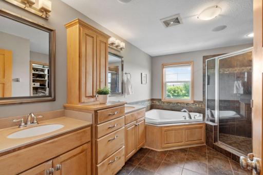 His and her vanities set into this solid oak cabinetry, beautiful soaking tub, tile flooring, and tiled walk-in shower.