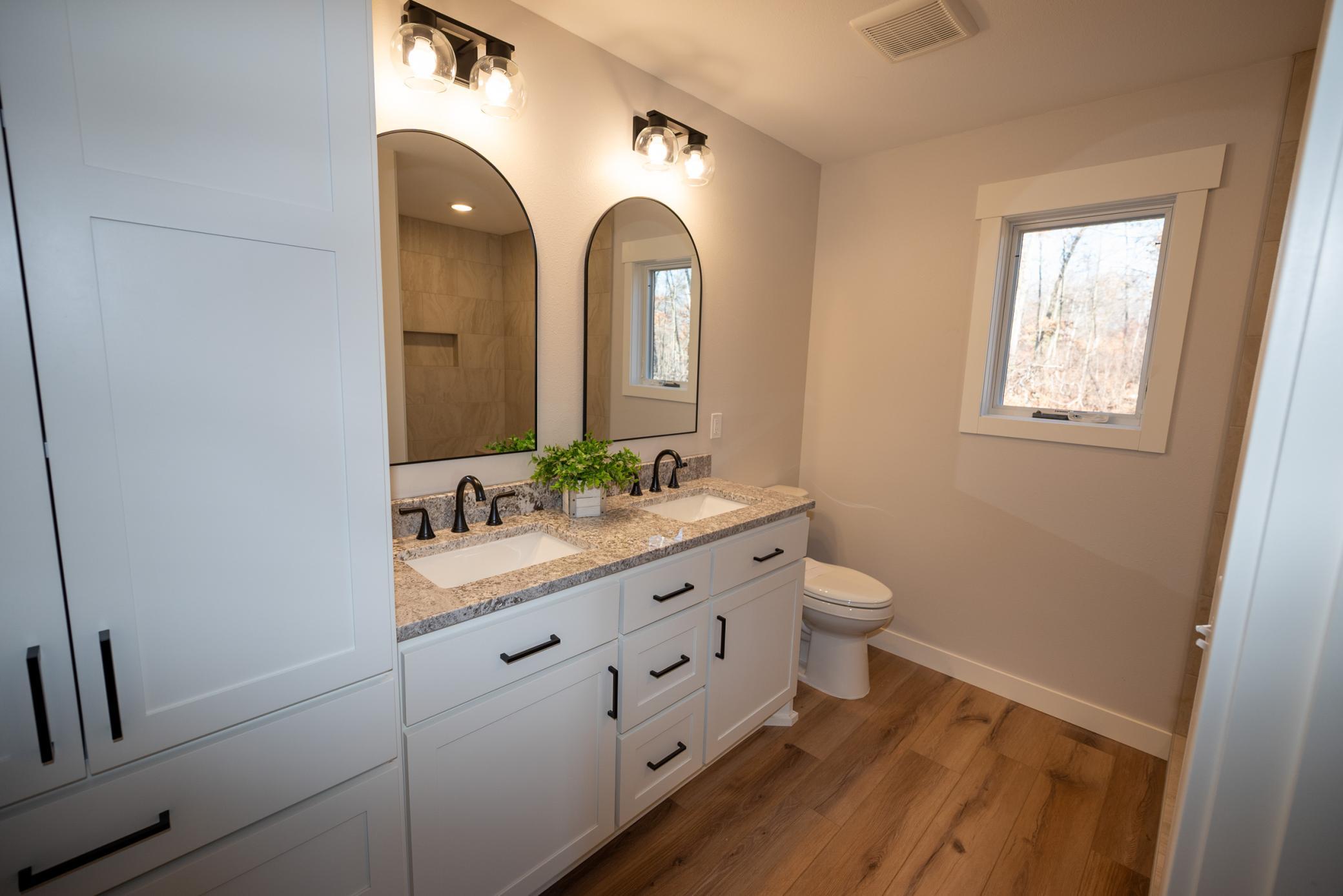 Stunning primary bathroom with custom built cabinets and tall pantry for great storage options!