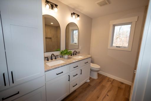 Stunning primary bathroom with custom built cabinets and tall pantry for great storage options!