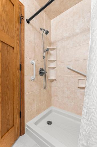 It includes a tiled walk-in shower and vanity with extra counter space, along with convenient hall closet storage with built-in shelving.
