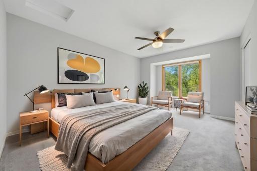 Upper level primary bedroom features a ceiling fan & beautiful views of the outdoor space. (virtually staged)