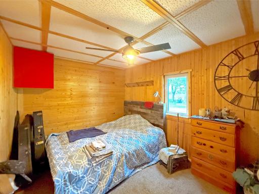 This cozy bedroom is filled with rustic charm, featuring warm knotty pine walls that create a bright comfortable retreat.