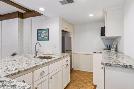 Entertain with ease in the lower-level second kitchen, featuring a refrigerator, brick accents, a prep sink, microwave, and generous counter seating