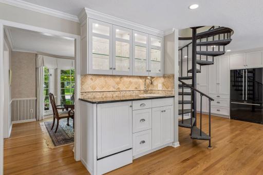 Elegant built-in wet bar featuring illuminated cabinetry, decorative tile backsplash, and a convenient prep sink.